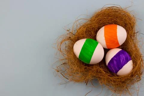Three colored eggs on a blue background in a copyspace nest for text Stock Photos