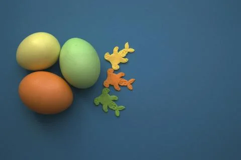 Three colored eggs lie on a purple background. Stock Photos