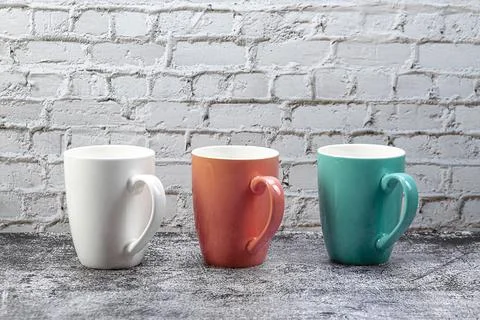 Three colored mugs are on the kitchen table. Stock Photos