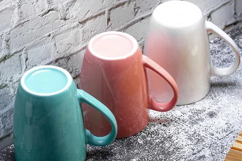 Three colored mugs are on the kitchen table. Stock Photos