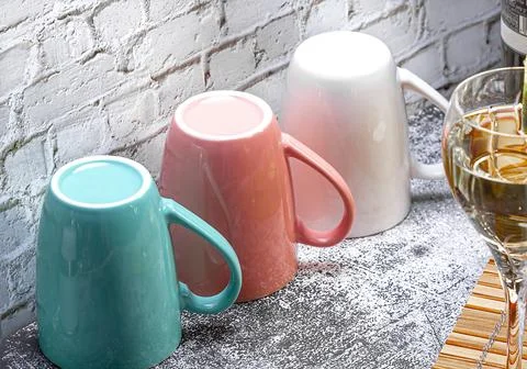Three colored mugs are on the kitchen table. Stock Photos