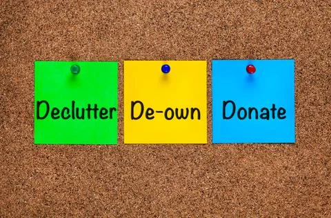 Three colored notes on corkboard with words Declutter, De-own, Donate. Stock Photos