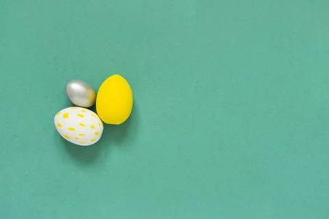Three colored painted eggs on green background Easter card with empty space f Stock Photos