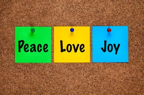 Three colored paper notes with words Peace, Love, Joy on a cork board Stock Photos