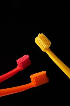Three colored plastic toothbrushes on a black background. Oral hygiene of the Stock Photos