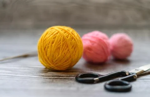 Three colored wool balls, knitting needles and scissors on the wooden backgro Stock Photos