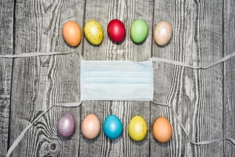 Three colored yellow easter eggs laying in medical mask. Stock Photos