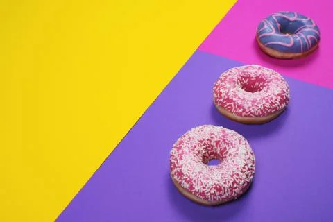 Three colorful donuts on multi colored background Stock Photos