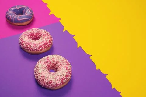 Three colorful donuts on multi colored background Stock Photos