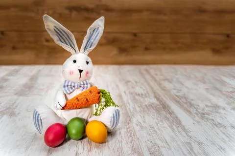 Three colorful Easter eggs in front of Easter bunny with wooden background Stock Photos