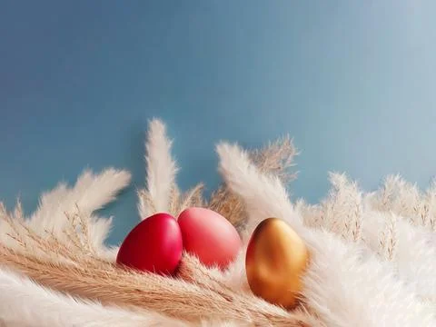 Three colorful Easter eggs resting in dried pampas grass and white feathers.. Stock Photos
