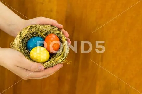 Three colorful eggs yellow orange blue with floral pattern in a straw nest ea Stock Photos