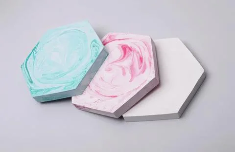 Three colorful marble-patterned tiles on a gray surface Stock Photos
