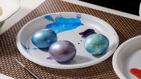 Three colorful painted Easter eggs lying on a white plate. 4K Stock Footage 122924999