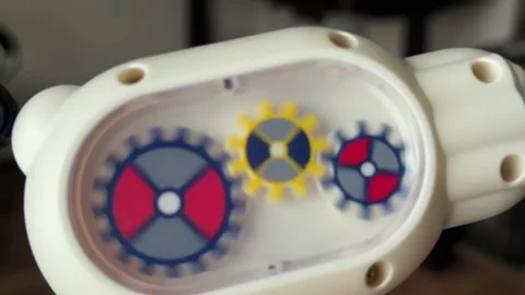Three colorful plastic gears inside a toy mechanism turning in tandem Stock Footage 321700225