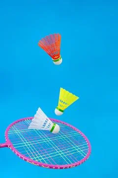 Three Colorful shuttlecocks and racket levitating isolated on blue backgrou.. Foto stock