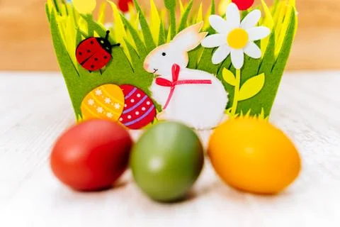 Three colourful blurred Easter eggs in front of decorative felt basket Stock Photos