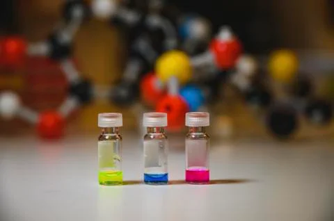 Three colourful solution in different glass vial on a white bench withmolecul Stock Photos