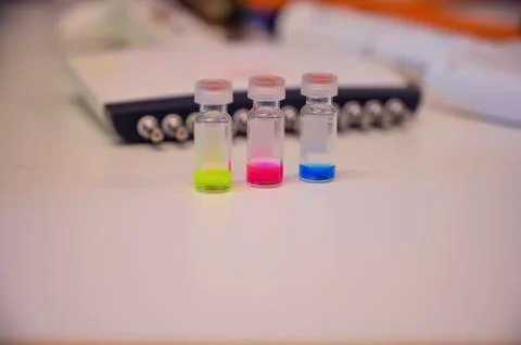 Three colourful solution in different LCMS glass vial on a white bench with m Stock Photos