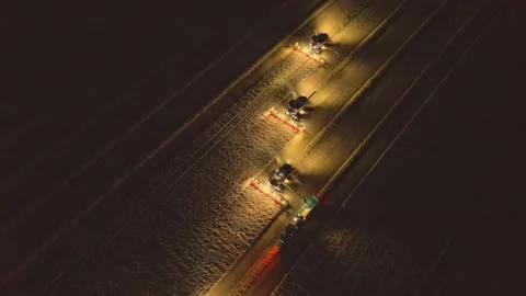 Three combine harvesters advancing across a cereal field at night while a Vídeo Stock 346251149