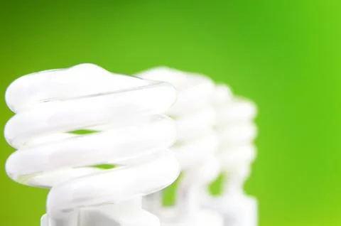 Three compact fluorescent light bulbs on green background Stock Photos