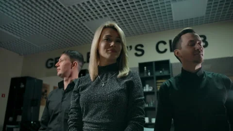 Three confident barbers stand in the interior of a barbershop. Stock Footage 133097862