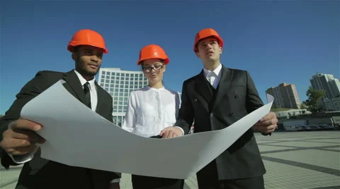 Three confident business architect in protective helmet standing on the site Stock Footage 42389459