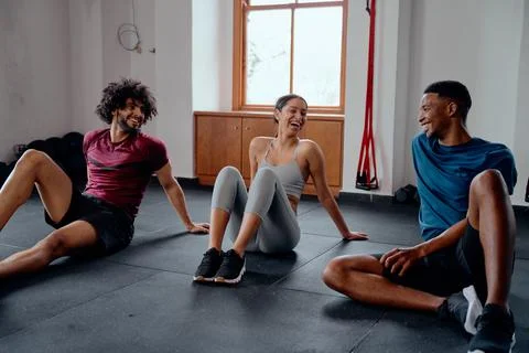 Three confident multiracial young friends in sportswear laughing at the gym Stock Photos