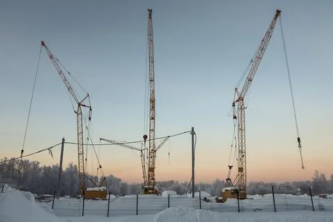Three construction cranes in cold winter against the background of frozen tre Stock Photos