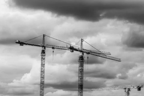 Three construction cranes with stormy sky above them Stock Photos