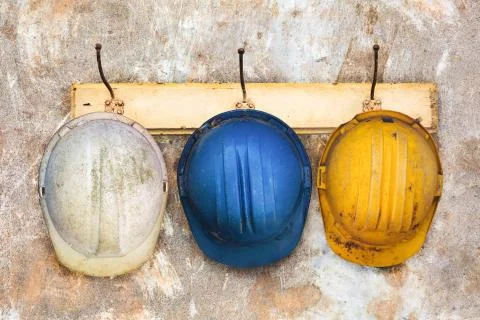Three construction helmets hanging on a hat-rack Фото
