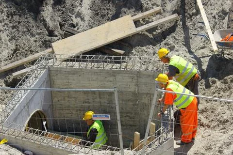 Three construction workers are working on the sewage system Stock Photos