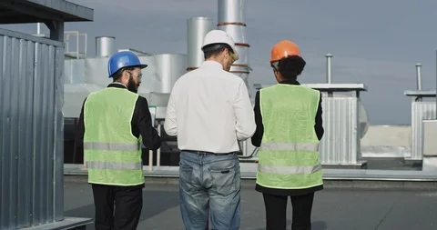 Three construction workers walk straight ahead while they discuss something Stock Footage 116248700