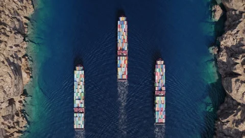 Three container ships navigating narrow rocky coastal strait Stock Footage 340332443