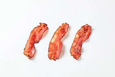 Three cooked bacon strips on clean surface Stock Photos