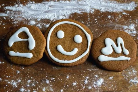 Three cookies with icing in the form of a smiley face and the letters A and M Stock Photos