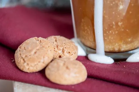 Three cookies next to cup of coffee with melted and drained cream on red napk Stock Photos