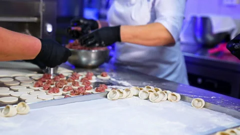 Three cooks collaborating in the kitchen producing meat ravioli. Stockbeeldmateriaal 195643106