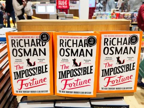 Three copies of The Impossible Fortune by Richard Osman displayed in a busy.. Stock Photos