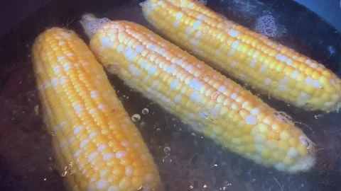 Three corn cobs boiling in water Video stock 174165289