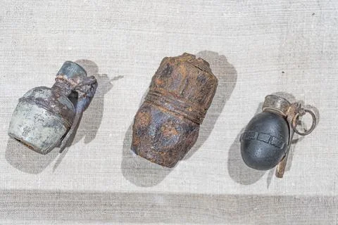 Three corroded, antique grenades on a light cloth backdrop Rounded shapes w.. Foto stock