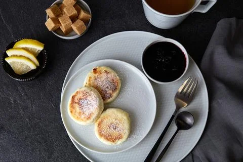 Three cottage cheese pancakes with jam lie on a gray plate Stock Photos
