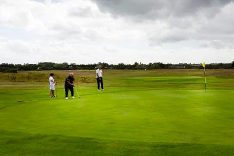 Three couples golf player playing golf in professional golf course. Stock Photos