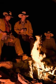 Three cowboys around a campfire Stock Photos