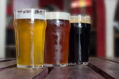 Three craft beer styles served in pint glasses on a wooden table Photos