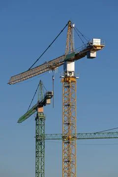 Three cranes in the evening light on a large construction site in the west of Stock Photos
