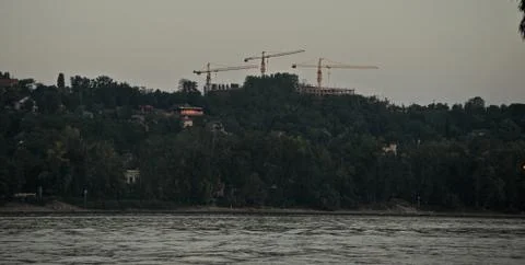 Three cranes on other side of river Danube Stock Photos
