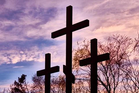 Three crosses in silhouette at sunset, dramatic sky Stock Photos