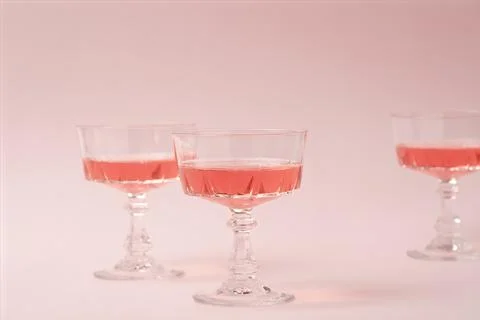 Three crystal glasses of rose sparkling wine or champagne on pastel pink Stock Photos