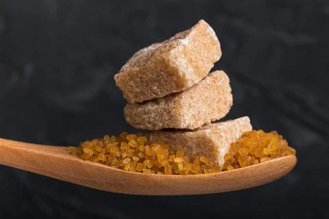 Three cubes of crushed cane sugar in a wooden spoon Stock Photos